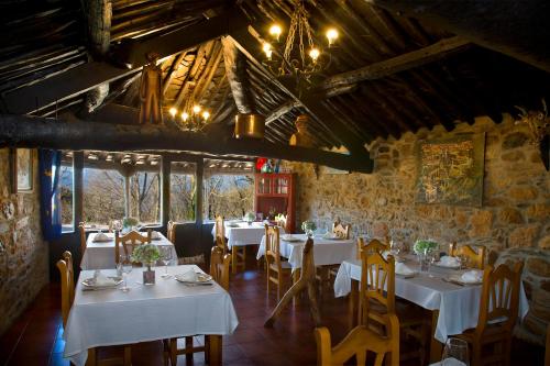 un restaurante con mesas y sillas blancas en una habitación en O Palleiro do Pe do Forno, en Orellán