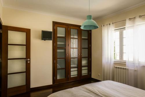 una camera con letto e finestra e luce a ciondolo di Villa Ramiro ad Azeitao