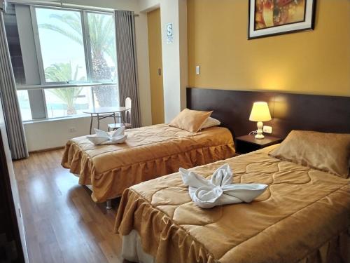 una camera d'albergo con due letti e una finestra di Hotel Dubái a Tacna