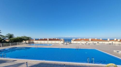 uma grande piscina com o oceano ao fundo em VILLA LORA Modern & New townhouse 2 Bedroom em Puerto de Santiago