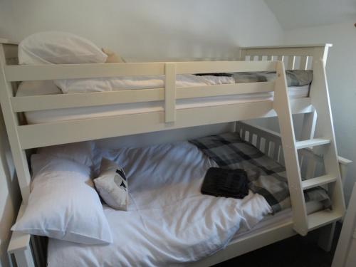 a white bunk bed with a black bag on it at Staddlestones Cottage in Bridport
