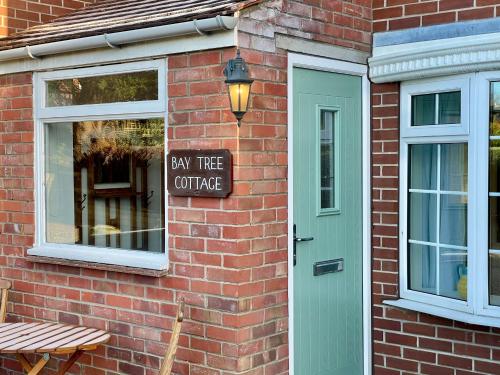 a brick building with a law tree coffee sign next to a door at Bay tree Cottage Hemsley in Helmsley