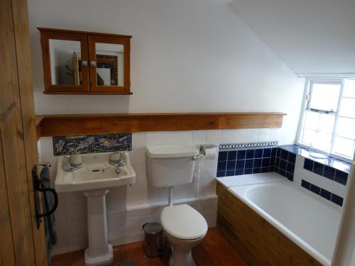 a bathroom with a toilet and a sink and a bath tub at Staddlestones Cottage in Bridport