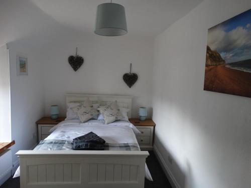 a bedroom with a white bed with hearts on the wall at Staddlestones Cottage in Bridport