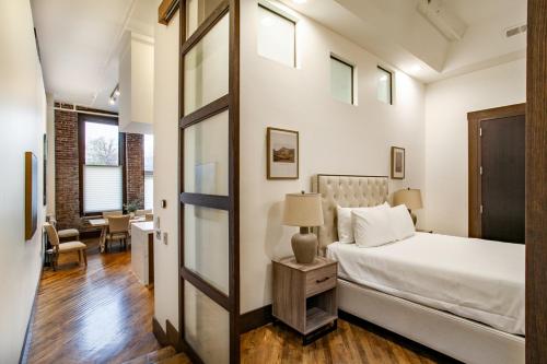 Jackson Jewel - Downtown Suite في نوكسفيل: غرفة نوم بسرير وطاولة مع مصباح