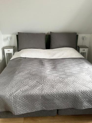 a bed with a silver comforter on top of it at Apothekergaarden Stege B&B in Stege