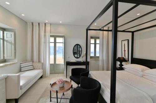 a bedroom with a bed and a couch and a table at Akrolithi Boutique Hotel & Suites in Oítilon