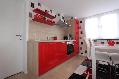 eine Küche mit roten Schränken und einem Tisch mit Stühlen in der Unterkunft Skyline in Ypern