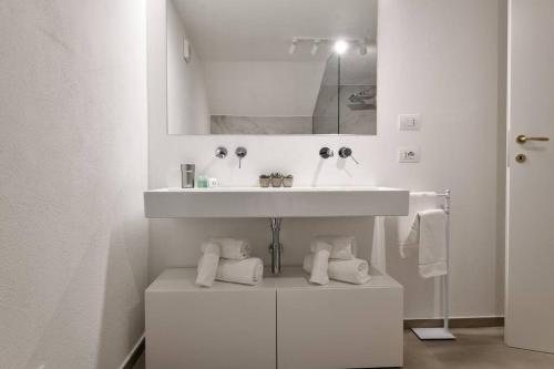 Un baño blanco con lavabo y espejo. en Amazing View - Exclusive Apartment Portu Frailis, en Àrbatax