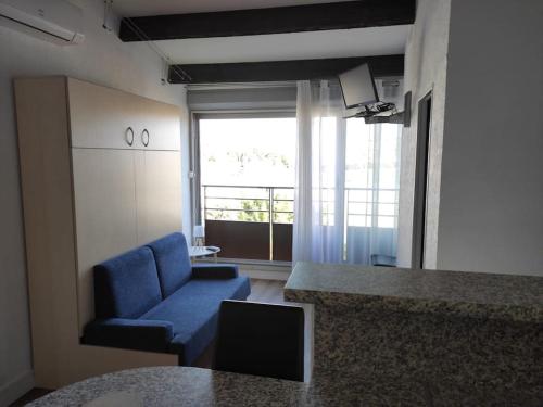 een woonkamer met een blauwe bank en een raam bij Vacances Ambassades du Soleil in Cap d'Agde