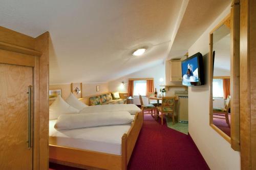ein Hotelzimmer mit einem großen Bett und einer Küche in der Unterkunft Apart Garni Mirabell in Kappl