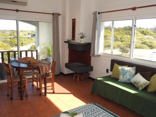 a living room with a table and a couch and windows at El Diablo Chic Colonial in Punta Del Diablo