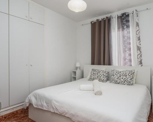 Un dormitorio blanco con una cama blanca y una ventana en Apartamento Adeje en Adeje