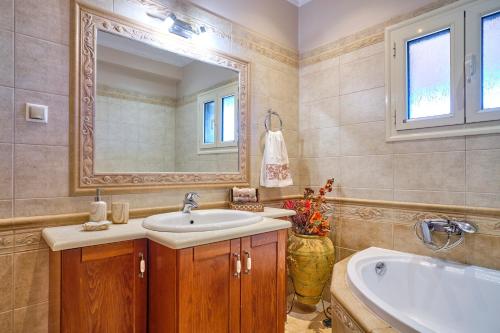 een badkamer met een wastafel, een bad en een spiegel bij Villa Melissi Afionas Corfu in Afionas