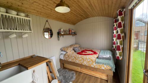 a small bedroom with a bed and a tub at Shepherds Hut at Cedar Gables in Lamberhurst