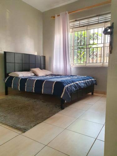 Ce lit se trouve dans un dortoir doté d'une fenêtre. dans l'établissement Dees shared home away from home, à Entebbe