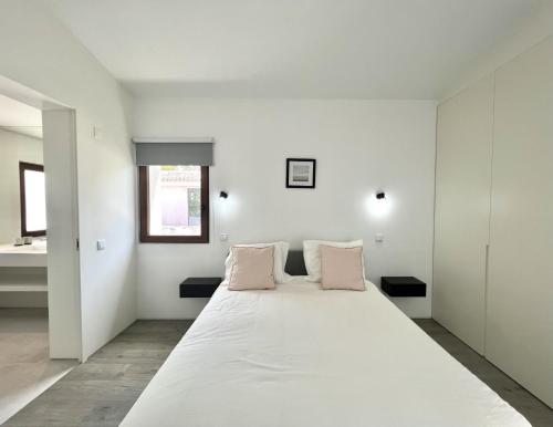 a white bedroom with a large bed with pink pillows at Vila Ruby - Private Pool by HD PROPERTIES in Vilamoura
