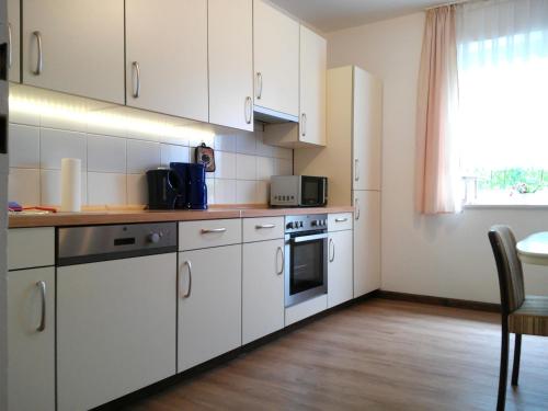 a kitchen with white cabinets and a table and a window at Ferienwohnung am Ellerbach in Hessisch Oldendorf