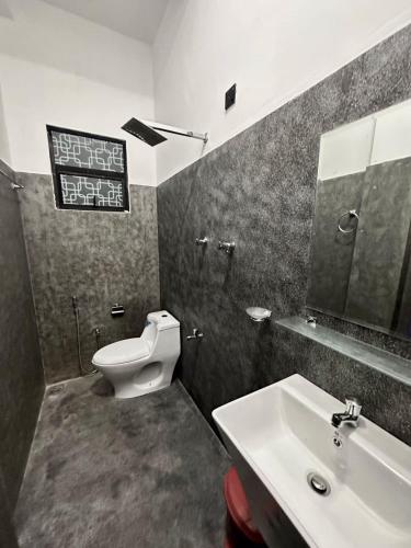 a bathroom with a toilet and a sink and a mirror at Villa 215 in Weligama