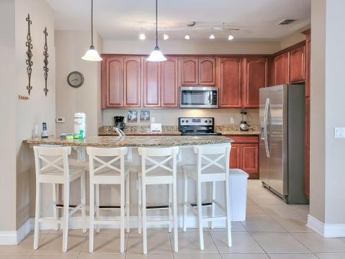 a kitchen with wooden cabinets and a kitchen island with bar stools at Spacious Vista Cay Condo near Universal Studios in Orlando