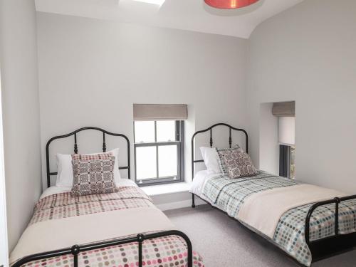 two beds in a room with white walls and a window at The Pottery in Newport Pembrokeshire