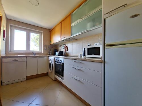 a kitchen with white appliances and a window at Apartamento Girassol Cabanas Gardens by Your Home Algarve in Cabanas de Tavira