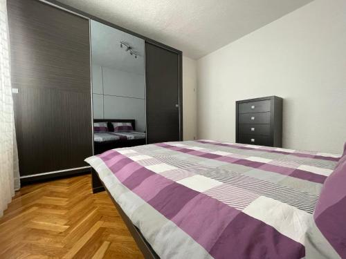 Schlafzimmer mit einem lila und weißen Bett und einem Spiegel in der Unterkunft Apartment Marina in Senj