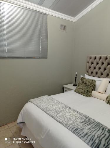 a bedroom with a large white bed with a window at Atholl Heights Homee in Westville