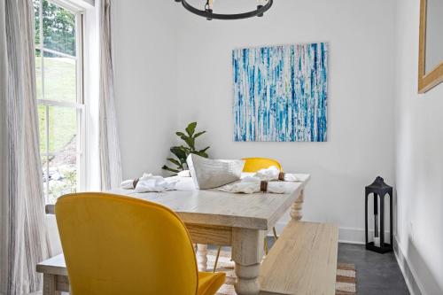 Un comedor con una mesa de madera y sillas amarillas. en Twilight House at Kowaliga Bay, en Eclectic