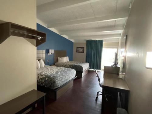 a hotel room with two beds and a desk at Baymont by Wyndham Bay City in Bay City