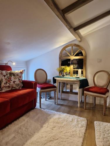 a living room with a red couch and a table at Le petit nid d'aigle - Giverny in Giverny