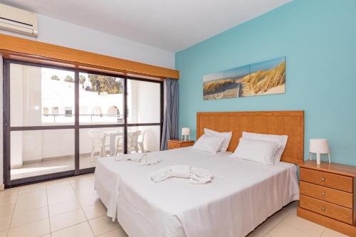 a bedroom with a bed and a large window at Natura Algarve Club in Albufeira