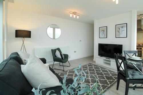 uma sala de estar com um sofá e cadeiras e uma televisão em The Hub by Pay As U Stay em Milton Keynes