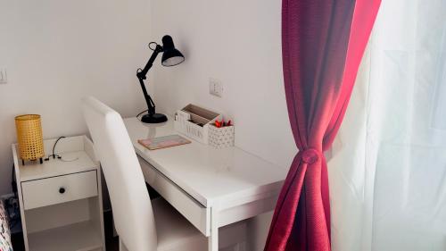 a white desk with a lamp and a red curtain at Gemelli-San Pietro-Trastevere-casa con posto auto in Rome