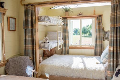 a bedroom with bunk beds and a window at the abberton shepherds hut in Evesham