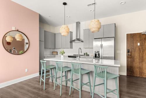 a kitchen with a large island with green chairs at Mason Lofts at West End in Nashville