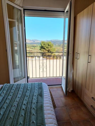 1 dormitorio con 1 cama y balcón con vistas. en La Morada de Salomé, en Ronda