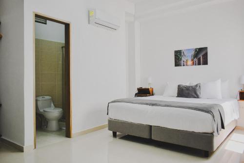 Habitación blanca con cama y aseo en Hotel El Marqués De Manga, en Cartagena de Indias