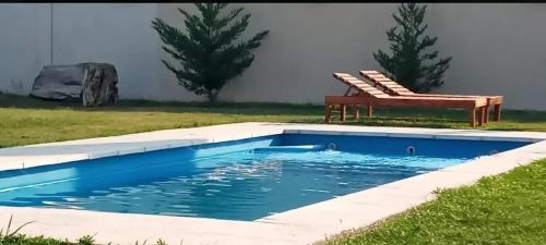un banco sentado junto a una piscina en Casa completa tipo campo. a 50 km de la capital Federal en General Rodríguez