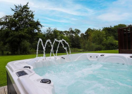 a hot tub with a water fountain in a yard at Paradise Lakeside Lodges in Wheldrake