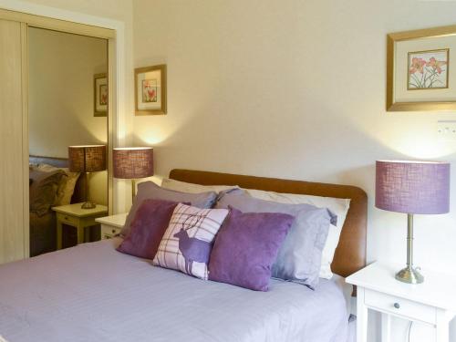 1 dormitorio con 1 cama con almohadas moradas en Fernilea Cottage, en Carbost