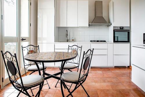 una mesa y sillas en una cocina con armarios blancos en Villa BeaBella, en Scicli