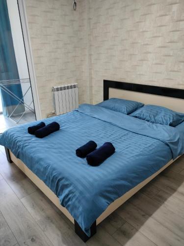 1 cama grande con sábanas azules y almohadas negras en ЖК Наурыз парк en Shymkent