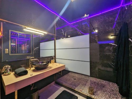 La salle de bains est pourvue d'un lavabo et de lumières violettes. dans l'établissement Suite Romantique Jacuzzi & Sauna privé Full options TV, à Perpignan