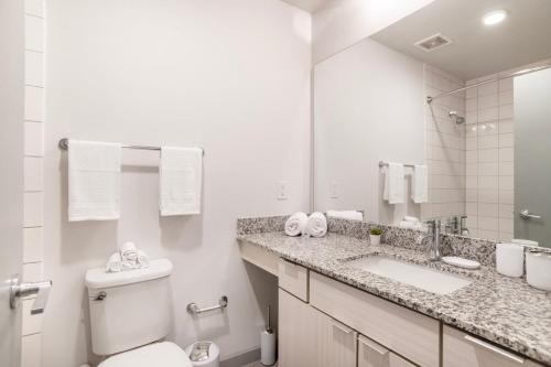 a bathroom with a toilet and a sink and a mirror at Stylish City Living Apartments with Free Parking in Midtown Atlanta in Atlanta