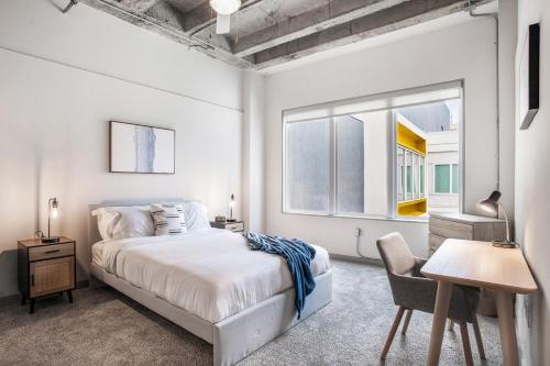 a white bedroom with a bed and a desk and a window at Stylish City Living Apartments with Free Parking in Midtown Atlanta in Atlanta