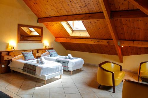 um quarto com 2 camas e uma cadeira amarela em Hôtel Mont Thabor Serre Chevalier em La Salle Les Alpes