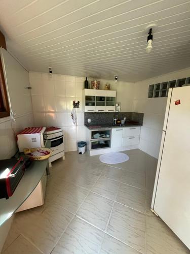 a kitchen with white cabinets and a white floor at Chalé Vista Azul in Domingos Martins