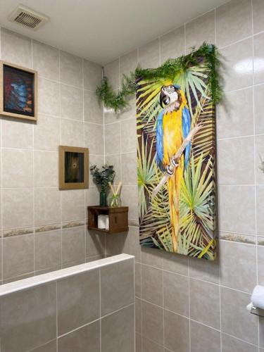 une salle de bains avec une peinture d'un perroquet sur le mur dans l'établissement Le Moulin du Modon, à Couffy