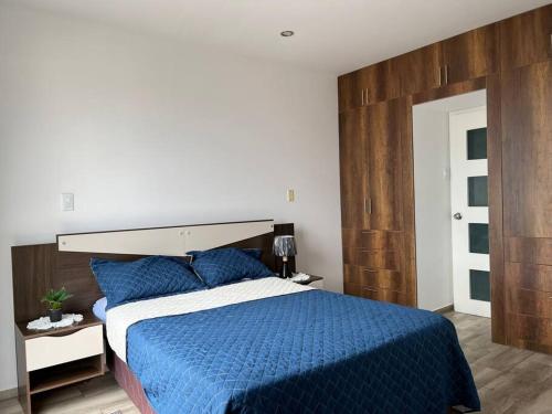 a bedroom with a blue bed with a wooden headboard at Apartamento Completo, cerca a Mall Aventura Plaza in Trujillo